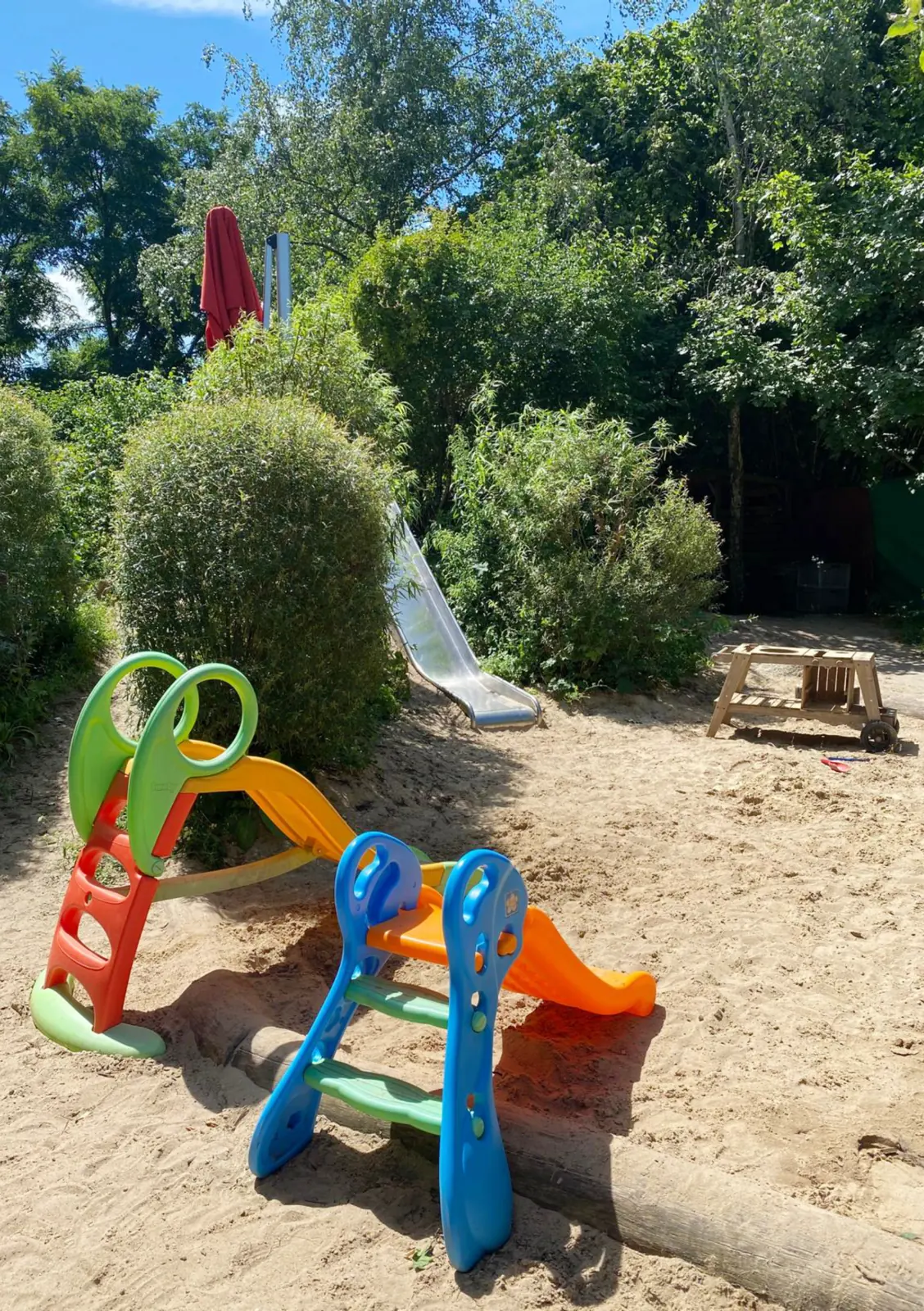 Sandbereich im Kita-Garten mit bunter Rutsche